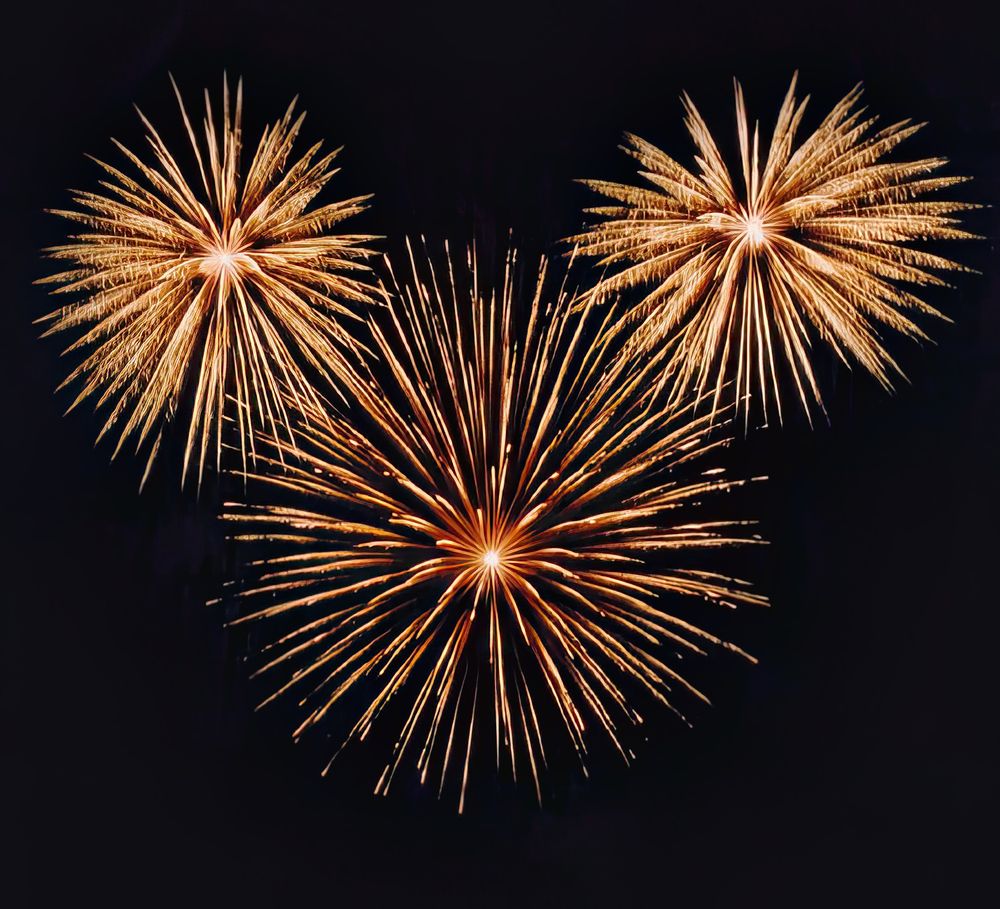 Three aerial fireworks bursts forming the shape of Mickey Mouse ears
